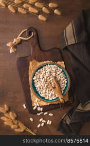 White beans in a ceramic bowl on a rustic kitchen countertop.