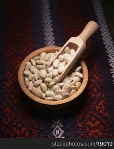 white beans in a wooden bowl on the background of the Ukrainian pattern