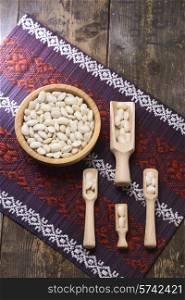 white beans in a wooden bowl on the background of the Ukrainian pattern