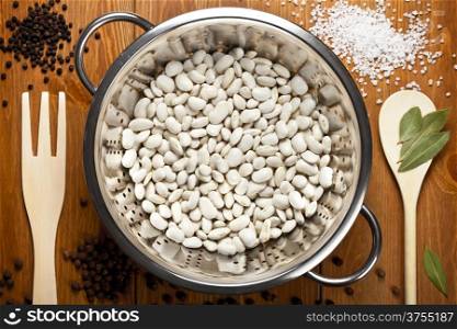 White beans with spices on wooden table background. Food composition. Top view