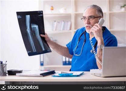 White bearded old doctor radiologist working in clinic 