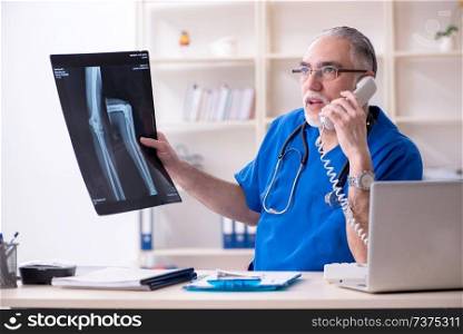 White bearded old doctor radiologist working in clinic 