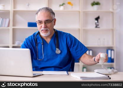 White bearded old doctor working in clinic 
