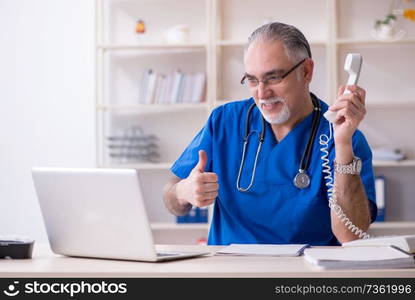 White bearded old doctor working in clinic 