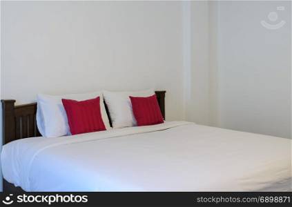 White bedroom with tidy King size bed and red pillows