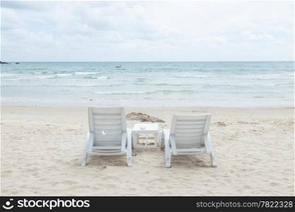 White bench and table on a beach by the sea. A relaxing holiday.