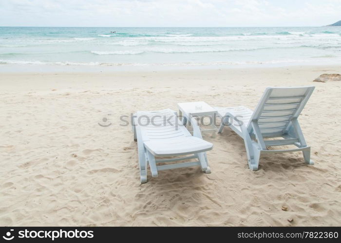 White bench and table on a beach by the sea. A relaxing holiday.