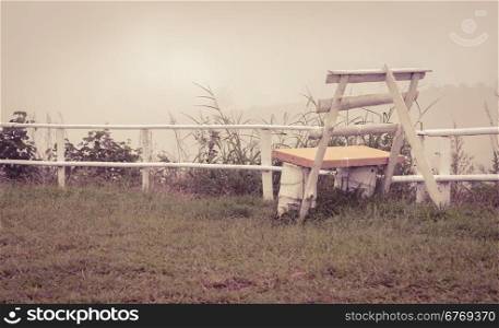 White bench in foggy morning on the mountain. Retro or vintage filtered image.