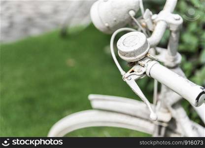 White bicycle in garden background. Vintage and nature concept. Close up and bike handle.