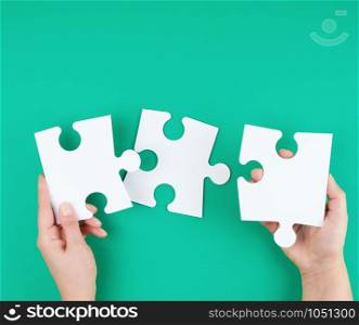 white big puzzles in female hand on green background, business concept, copy space