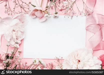 White blank card with pastel flowers and ribbon on pink pale background, floral frame. Creative greeting, Invitation and holiday concept