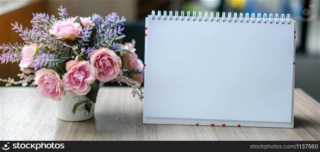 white blank paper Calendar on wooden table with flower. Copy space for your text