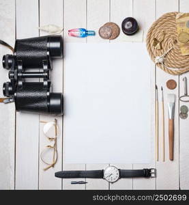 White blank paper sheet with lot of different creative stuff around it on wooden table