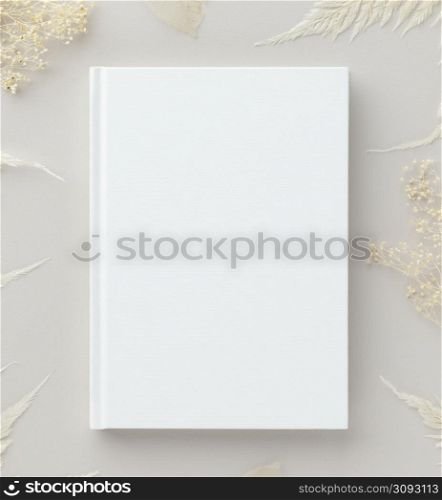 White book mockup with dry flowers on a beige background, flat lay, mockup