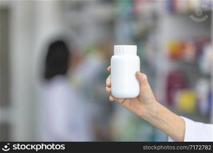 white bottle medicine on hand pharmacist in pharmacy store