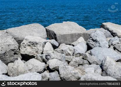 White boulders and rocks against rippled blue water.
