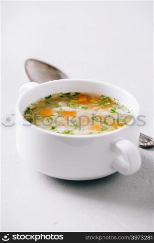 White bowl of homemade vegetable soup on concrete background, close up