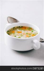 White bowl of homemade vegetable soup on concrete background, close up