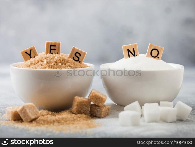 White bowl plates of natural brown and white refined sugar and cubes on light background.Yes and no letters. Healthy and unhealthy concept.