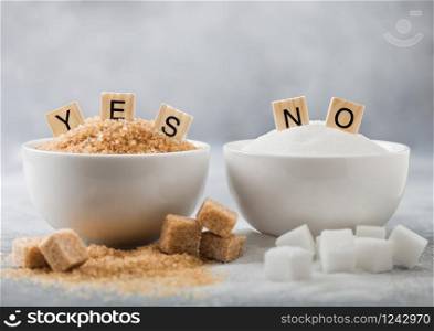 White bowl plates of natural brown and white refined sugar and cubes on light background.Yes and no letters. Healthy and unhealthy concept.