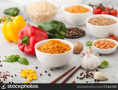 White bowl plates with boiled long grain basmati rice with vegetables and mushrooms on light background with sticks and paprika pepper with corn,garlic and basil with beans and peas.