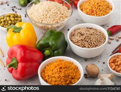 White bowl plates with boiled long grain basmati rice with vegetables and mushrooms on light background with sticks and paprika pepper with corn,garlic and basil with beans and peas.