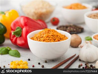 White bowl plates with boiled long grain basmati rice with vegetables and mushrooms on light background with sticks and paprika pepper with corn,garlic and basil.