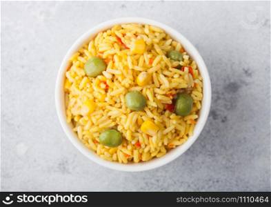 White bowl with boiled organic basmati vegetable rice on light background. Yellow corn and green peas with paprika slices.