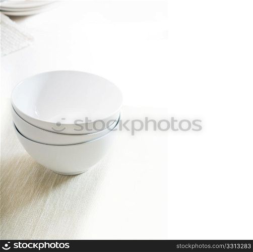 white bowls stacked over white table cloth with dishes on background,huge wite copyspace