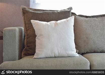 White, brown and grey velvet pillows setting up on sofa in living room interior