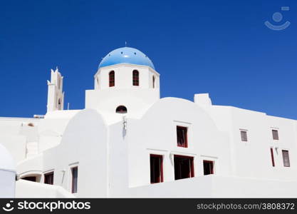 White buildings and church with blue dome in Oia or Ia on Santorini island, Greece. Traditional architecture and famous tourist attraction
