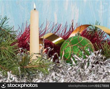 White candle and a green Christmas ball among the New Year&rsquo;s tinsel. In the frame of snow in the congratulatory inscription