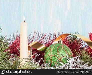 White candle and a green Christmas ball among the New Year&rsquo;s tinsel. In the frame of snow in the congratulatory inscription