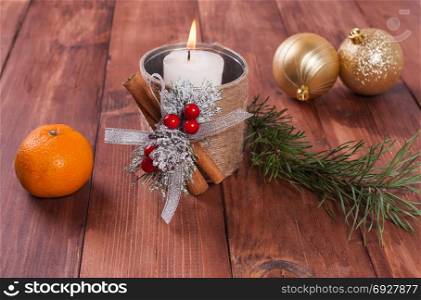 White candle in a homemade candlestick, Christmas balls and spruce branches