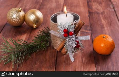 White candle in a homemade candlestick, Christmas balls and spruce branches