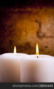 White candles burning with a textured vintage background