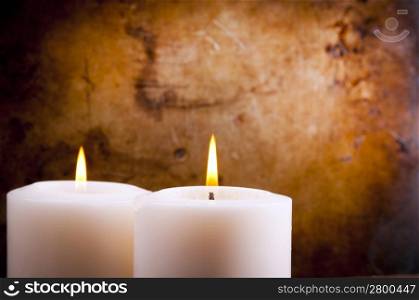 White candles burning with a textured vintage background