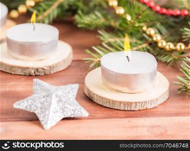 White candles on a wooden stand against a background of a blurred background of spruce fir