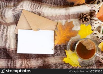 white card fall invitation, leaves and coffee on wooden autumn background, top view with copy space on white paper note. Fall leaves autumn background
