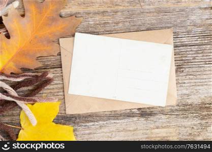 white card fall invitation, leaves and coffee on wooden autumn background with copy space on white paper note. Fall leaves autumn background