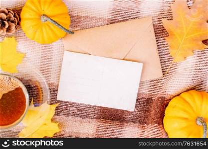 white card fall invitation, pumpkins, leaves and coffee on woolen plaid autumn background, retro toned. Fall leaves autumn background