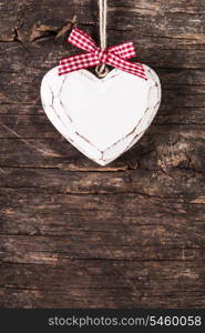 White carved heart over old wooden background, valentine decor