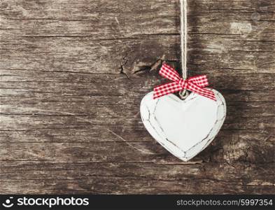 White carved heart over old wooden background, valentine decor