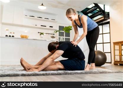 White caucasian man learning yoga at home. Female instructor or trainer coaching and adjust correct pose to student. Workout healthy lifestyle and Yoga health delivery concept.