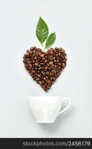 White ceramic coffee cup and coffee beans in shape of heart on white background, flat lay