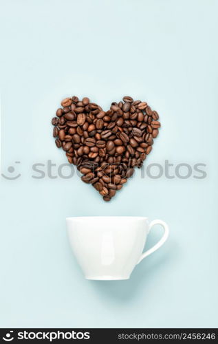 White ceramic coffee cup and coffee beans in shape of heart on blue background, flat lay