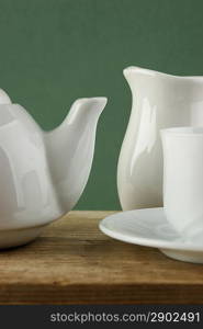 white ceramic coffee set on old wooden table over green background