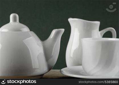 white ceramic coffee set on old wooden table over green background