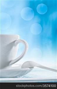 white ceramic cup with spoon on blurry blue background