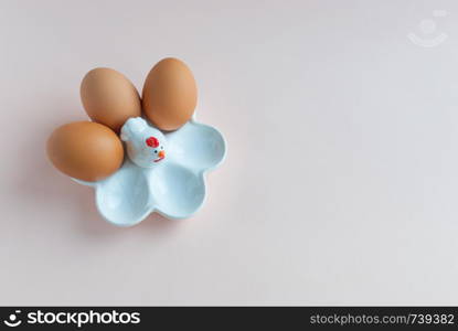 White ceramic egg holder with egg on pink soft background. Ceramic chicken egg holder. Top view. White ceramic egg holder with egg on pink soft background. Ceramic chicken. Top view